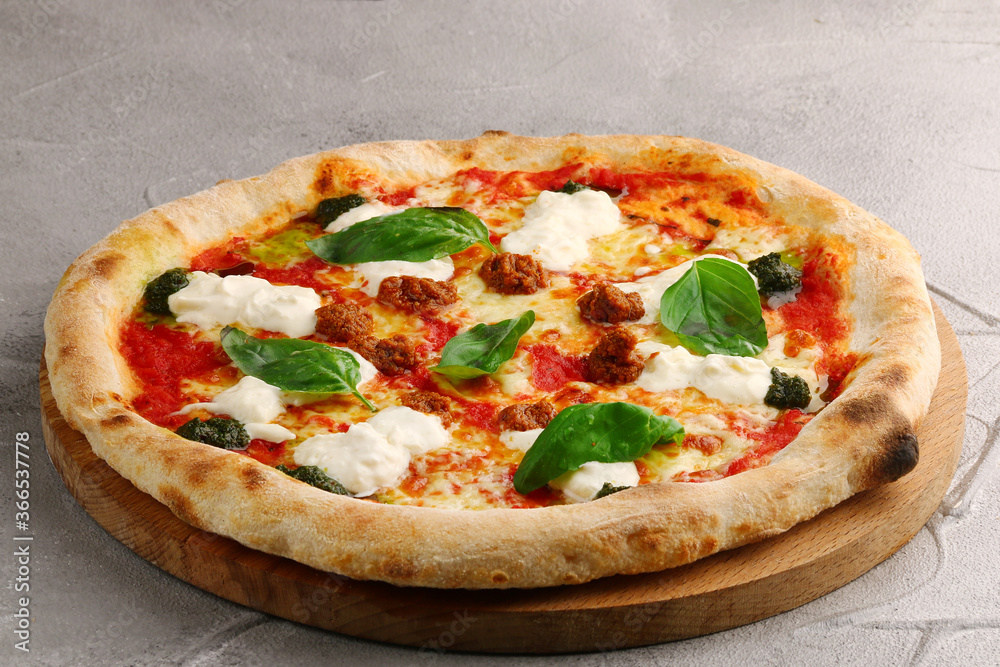 strachatella pizza closeup on light concrete or stone background. pizza with meat, pesto, tomatoes and stracciatella cheese