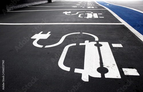 Electric car charging station in indoor parking garage. Empty parking spots with the electric charging symbol painted on.