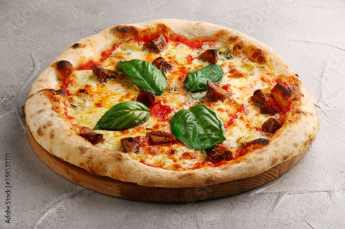 pizza with mushrooms, tomato and basil close up on light concrete or stone table and black background for copy space