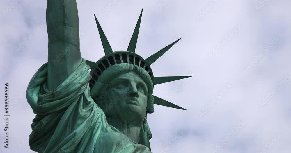 Close up view of the Statue of Liberty face and crown on a partly cloudy day in New York City.