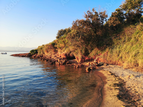 Orange rocky cliffs, sandy beach and Adriatic sea. Island Vir in Croatia on sunset.