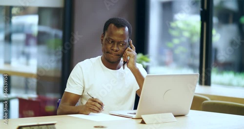 Wallpaper Mural One young African businessman focus working in the office using laptop talking on the mobile phone writing notes on the book Black working people 4k footage  Torontodigital.ca