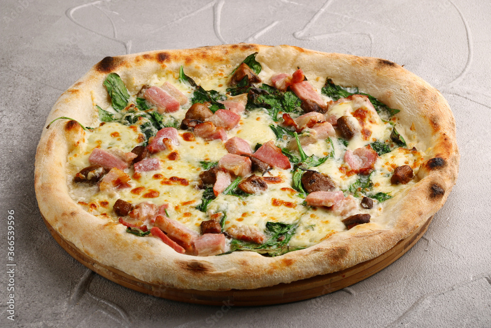 pizza with meat, mushrooms and spinach close up on gray concrete background. italian pizza top view