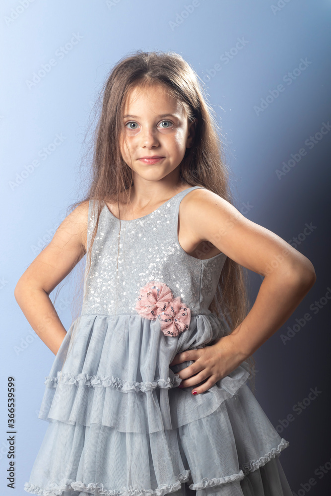A beautiful long-haired girl with her favorite items in her hands on a light background in a gray dress with sequins. Foreground. Quarantine, games at home. A beautiful long-haired girl with her favorite items in her hands on a light background in a gray dress with sequins. Foreground. Quarantine, games at home.