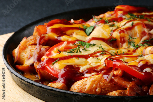 frying pan with potatoes meat and tomatoes on black concrete background. mexican food concept. potatoes fried in a pan