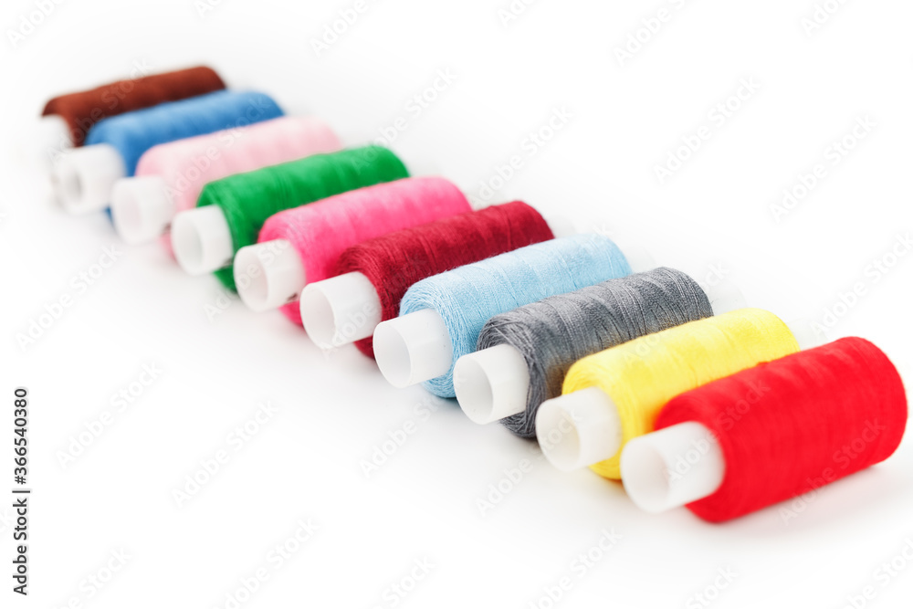 Sewing threads of different colors on reels on a white background. Free space, close-up. Isolate Sewing threads of different colors on reels on a white background. Free space, close-up. Isolate