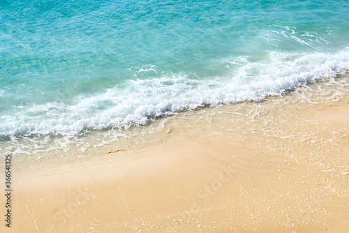 Water splashing. Crystal clear sea water beating against the rocks and cliffs. Blue sky above the beach in the sun zenith refreshing drops of ocean water. Sea waves break on the shore after a storm