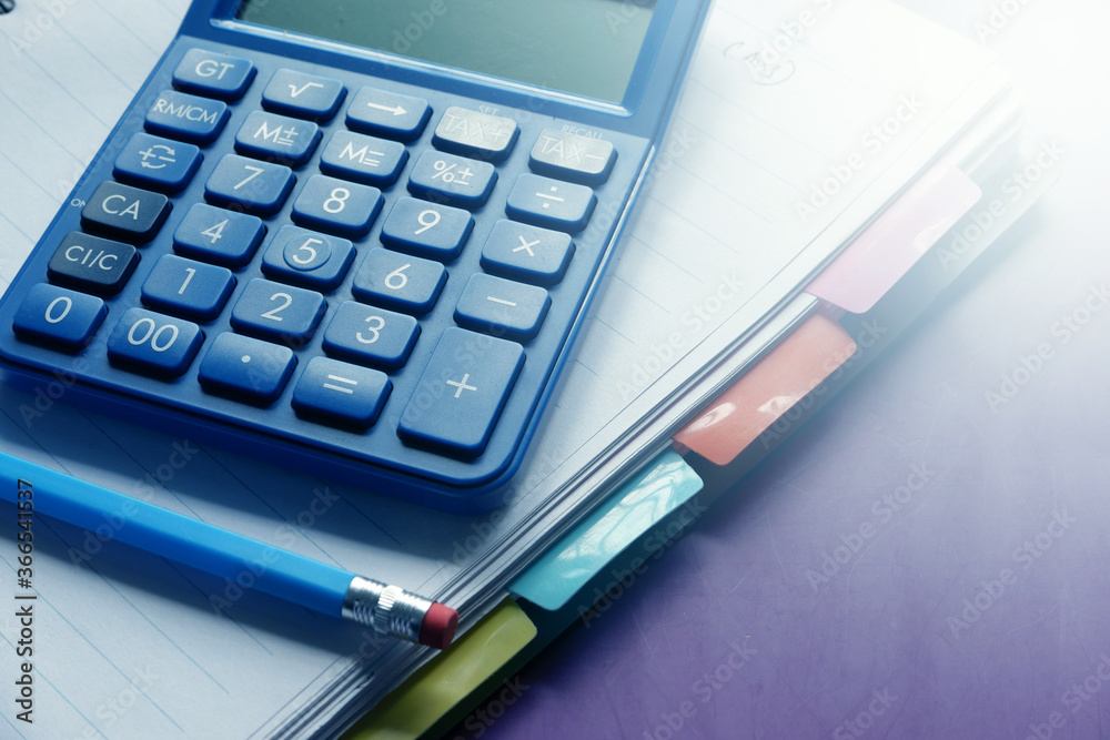 Close up of blue calculator and notepad on color background Close up of blue calculator and notepad on color background
