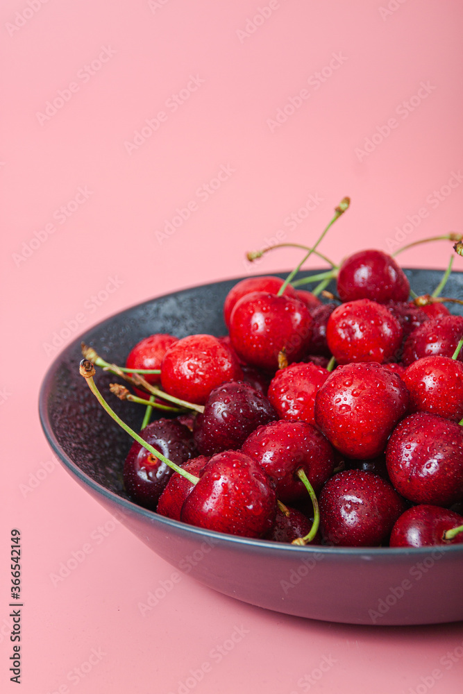 Cherry with leaf on plate and water dropsand on grey stone table Cherry with leaf on plate and water dropsand on grey stone table