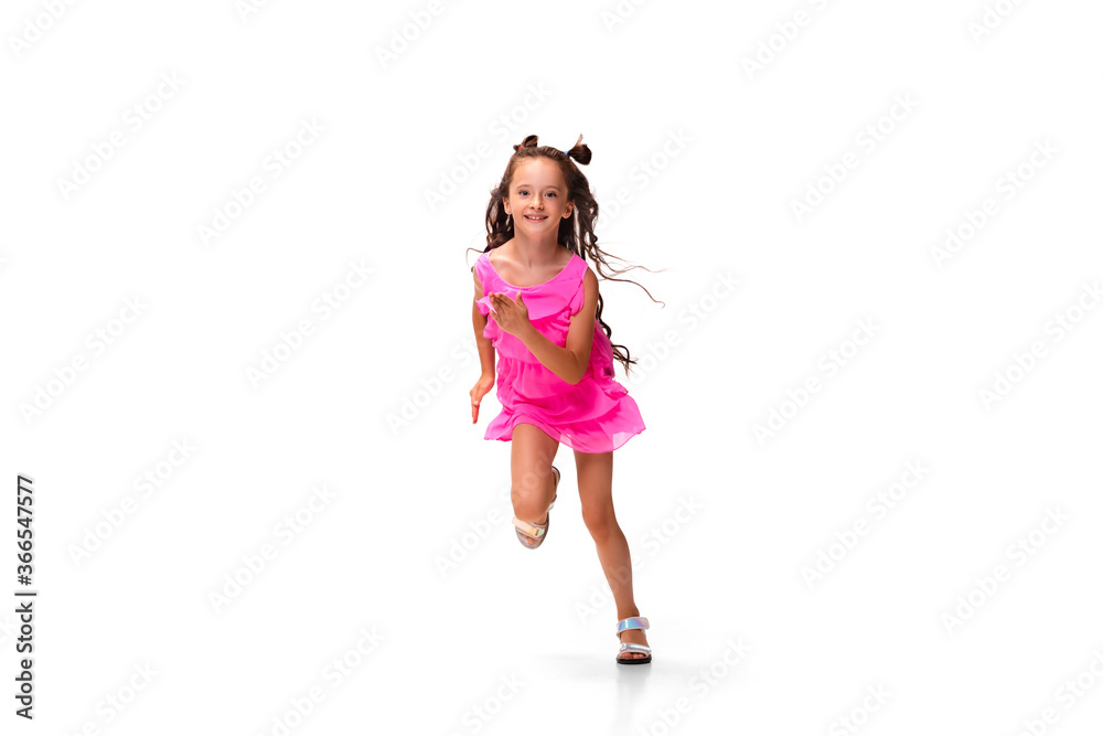 Happy child, little and emotional caucasian girl jumping and running isolated on white background. Looks happy, cheerful, sincere. Copyspace for ad. Childhood, education, happiness concept.