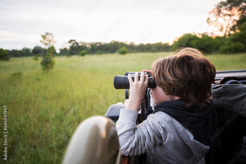 A six year old boy using binoculars seated in a safari jeep. A six year old boy using binoculars seated in a safari jeep.