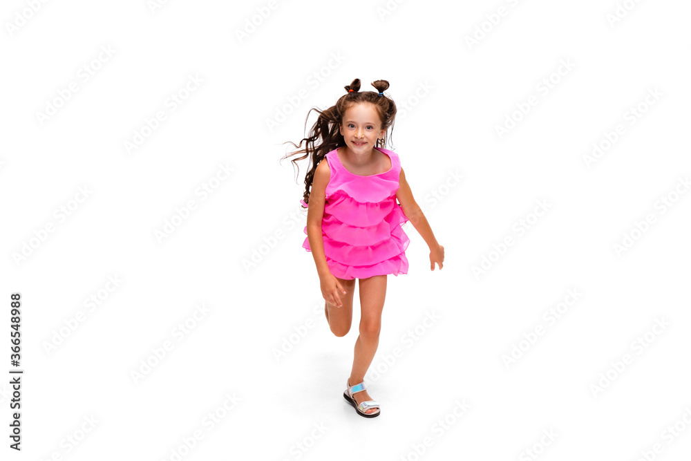 Happy child, little and emotional caucasian girl jumping and running isolated on white background. Looks happy, cheerful, sincere. Copyspace for ad. Childhood, education, happiness concept.