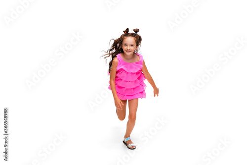 Happy child, little and emotional caucasian girl jumping and running isolated on white background. Looks happy, cheerful, sincere. Copyspace for ad. Childhood, education, happiness concept.