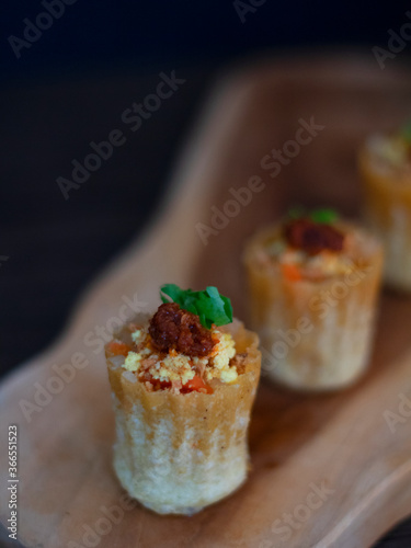 "Kueh Pie Tee" in Dark Background with Copy Space. Southeast Asian pastry shell filled with turnip, eggs, prawns. Peranakan Snacks from Singapore and Malaysia.