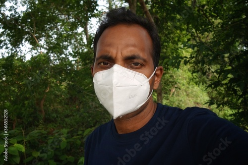 A young man covering his face with an anti pollution N95 mask while going outside during COVID-19 pandemic.