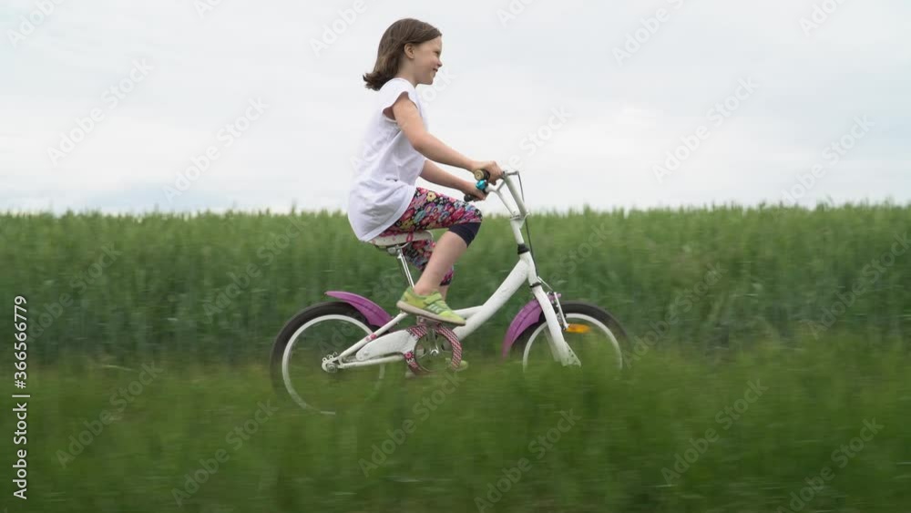Little girl rides a bicycle on a scenic rural road Little girl rides a bicycle on a scenic rural road