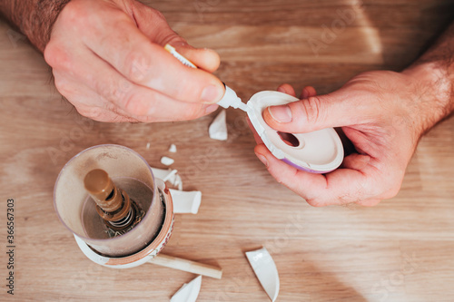 Male hands glue together fragments of ceramic dishes - superglue for repairing hard materials photo