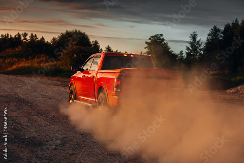 Pickup truck car in motion at country road with clouds of dust photo