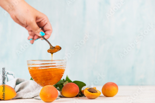 Apricot jam in a glass plate and ripe apricots on a white table. Copy space.