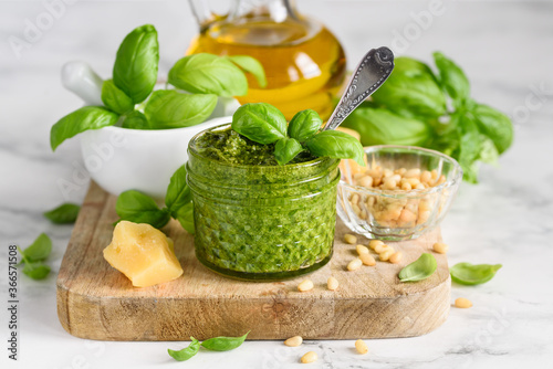 Canvas Print Homemade basil pesto sauce in a glass jar on a wooden board