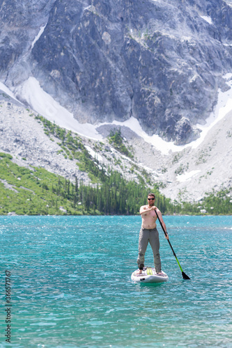 Man paddle boarding on green alpine lake, granite mountain in the back photo