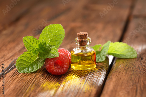 Mint leaves and raspberry berry on a wooden table, raspberry oil.