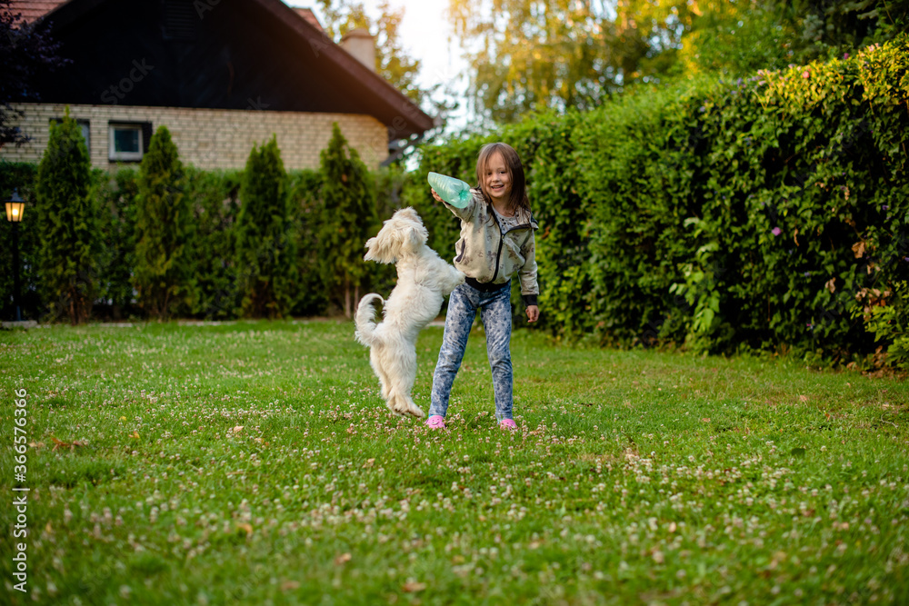 Obraz premium Cute girl with a dog in the garden