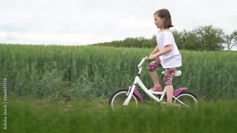 Little girl rides a bicycle on a scenic rural road Little girl rides a bicycle on a scenic rural road
