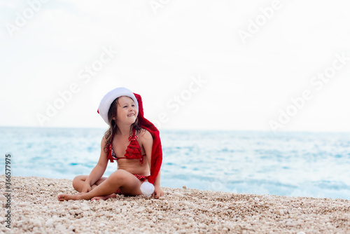Little girl with Santa hat on the beach