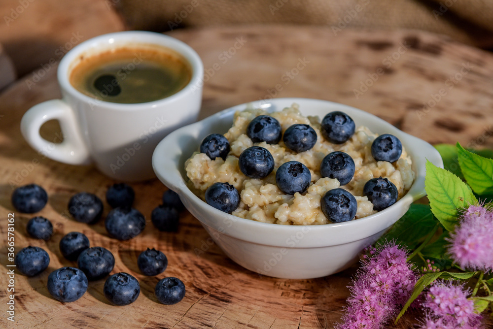 Oatmeal with blueberries for breakfast with coffee on a wooden table. Traditional healthy breakfast. Oatmeal and espresso. Close-up Oatmeal with blueberries for breakfast with coffee on a wooden table. Traditional healthy breakfast. Oatmeal and espresso. Close-up