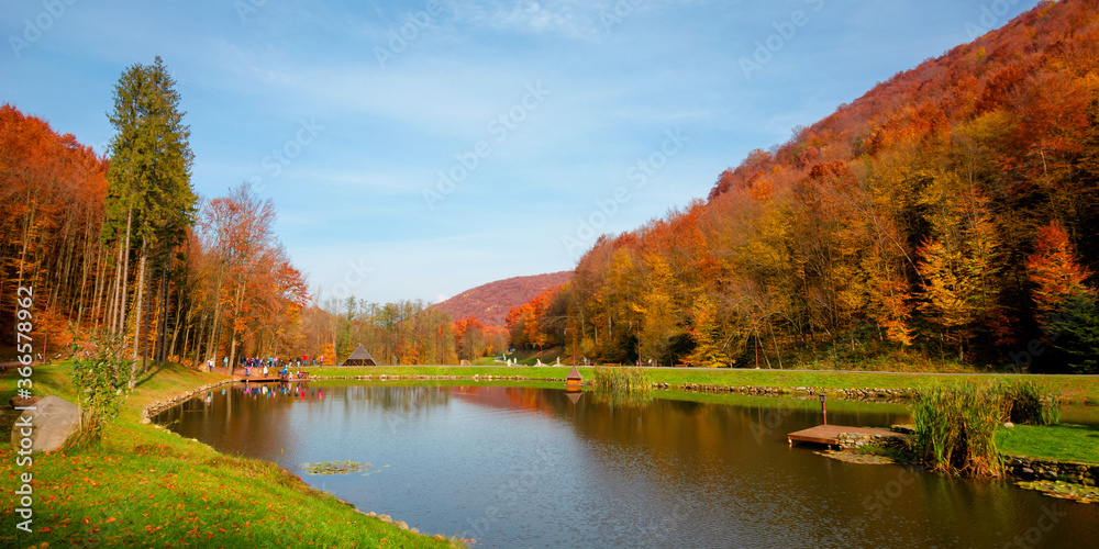 small lake in autumn park. forest on the hills in fall colors. green grass on the shore. beautiful nature scenery on a sunny day