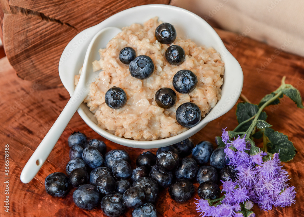 Oatmeal with blueberries. Healthy breakfast. Wooden background. Top view. Selective soft focus. Shallow depth of field. Oatmeal with blueberries. Healthy breakfast. Wooden background. Top view. Selective soft focus. Shallow depth of field.