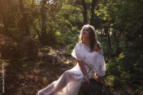 Beautiful mystery gothic woman in long white dress in autumn forest.