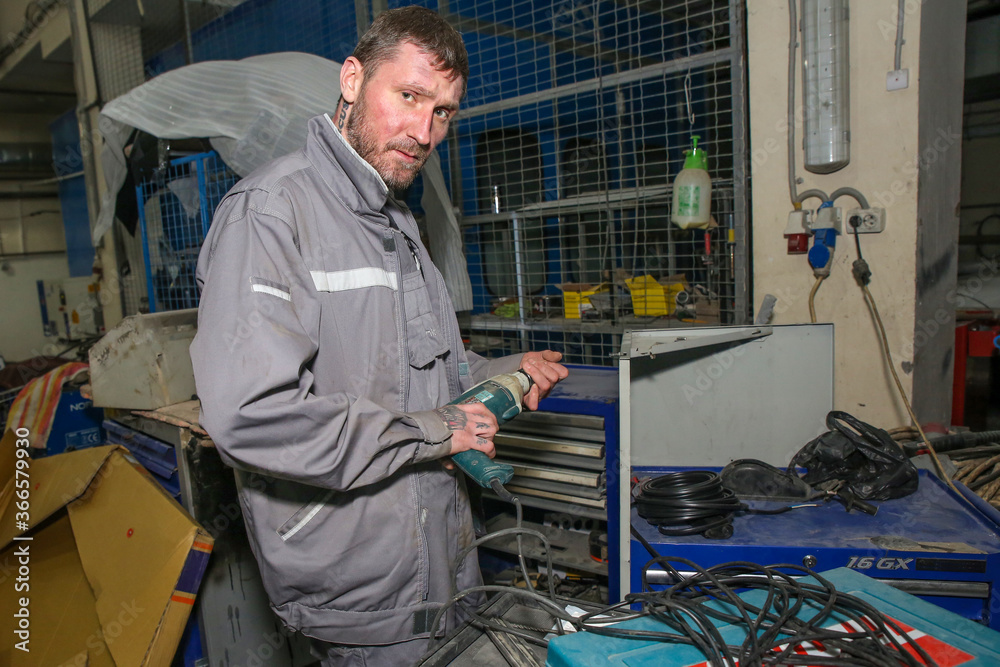a man with a drill in a car repair shop a man with a drill in a car repair shop