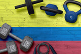 Colombia sports club concept. Top view of heavy weight plates with iron bar on national background.