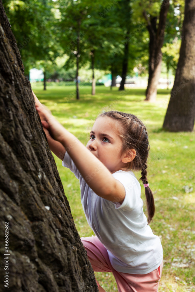 little cute caucasian girl playing cheerful in green park at summer,climbing on tree, lifestyle people concept little cute caucasian girl playing cheerful in green park at summer,climbing on tree, lifestyle people concept