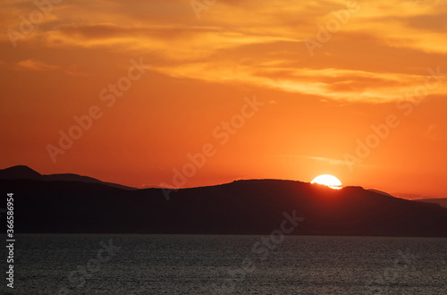 Sunrise  sunset clouds. Twilight  dusk cloudy sky over sea water  dark land horizon