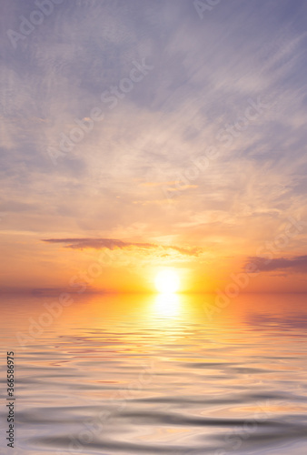 Sunset over a calm ocean with bright sunrays and clouds. © Sviatoslav Khomiakov