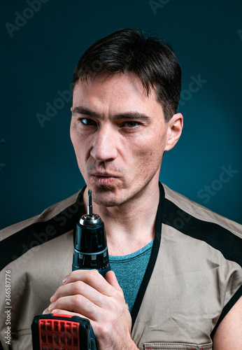 Repairman Worker Holding Electric Drill Posing To Camera Over blue Studio Background. Building Tools Concept