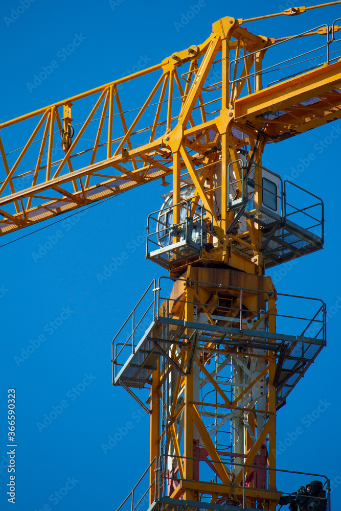 Yellow tower crane working on building against blue sky, selective focuse