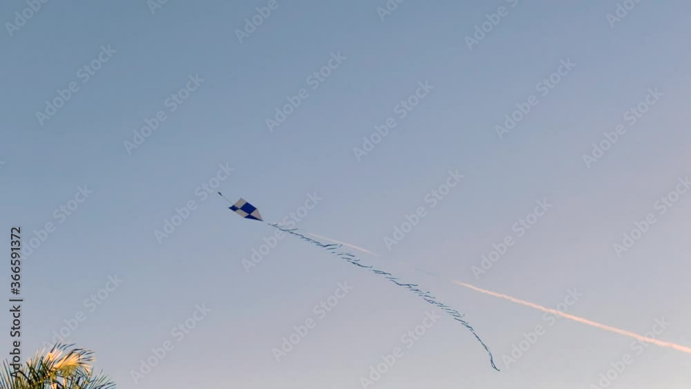 Kite flying on a regular wind and also falling due to the its lack under a blue sky as background