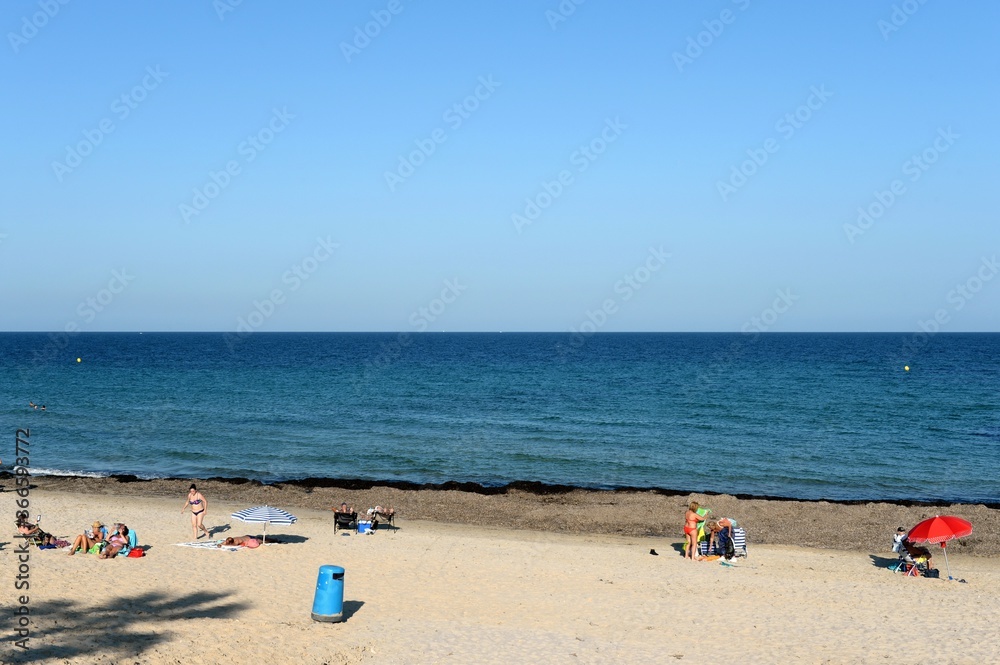 People relax on a sandy beach in Torre de La Horadada, Spain