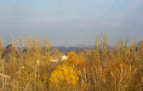 Autumn urban landscape on a Sunny day - yellow and colorful autumn trees, the sky with clouds with autumn haze