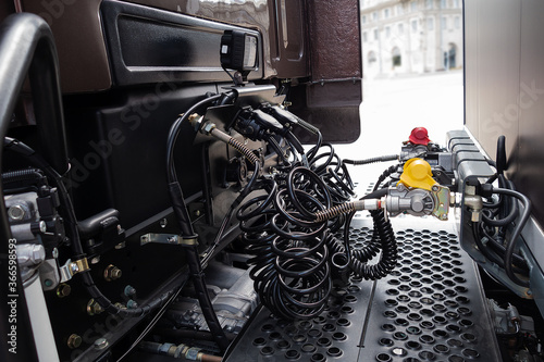 Coiled control and electrical cables connect the cab and semi-trailer of the truck.