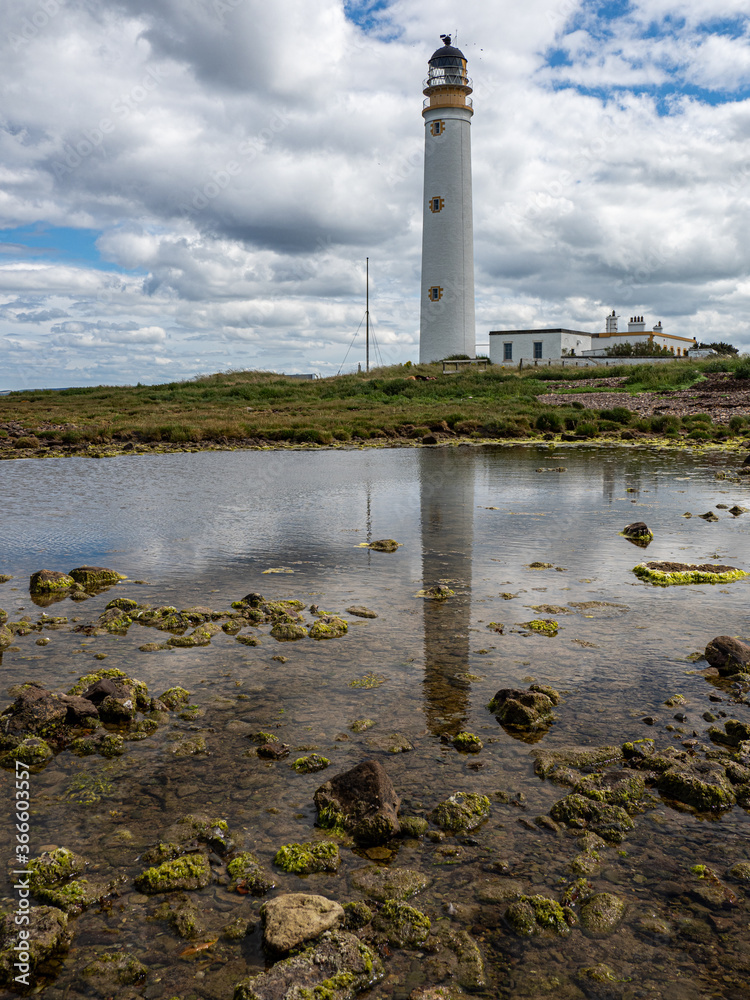 Reflections of Barns Ness Lighthouse in the rock pools