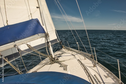 A sailing boat sailing upwind on a sunny bright calm day on the open sea.