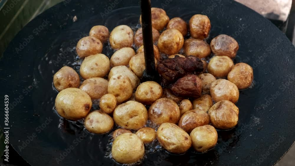 Young whole potatoes fried in boiling oil to a large frying pan over an open fire. Young whole potatoes fried in boiling oil to a large frying pan over an open fire.