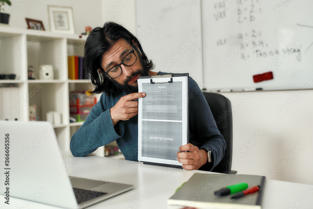 Teaching programming languages. Young male teacher explaining new theme while teaching java online through web camera while working from home Teaching programming languages. Young male teacher explaining new theme while teaching java online through web camera while working from home