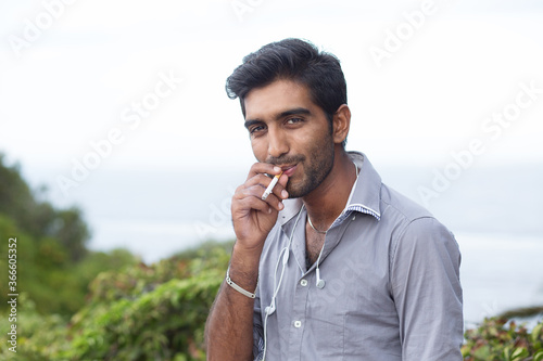 Happy ethnic man smoking cigarette, smiling, thinking