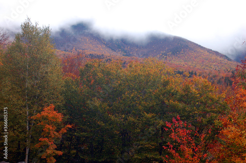 Storm clouds rill over the mountain tops covered in autumn foliage